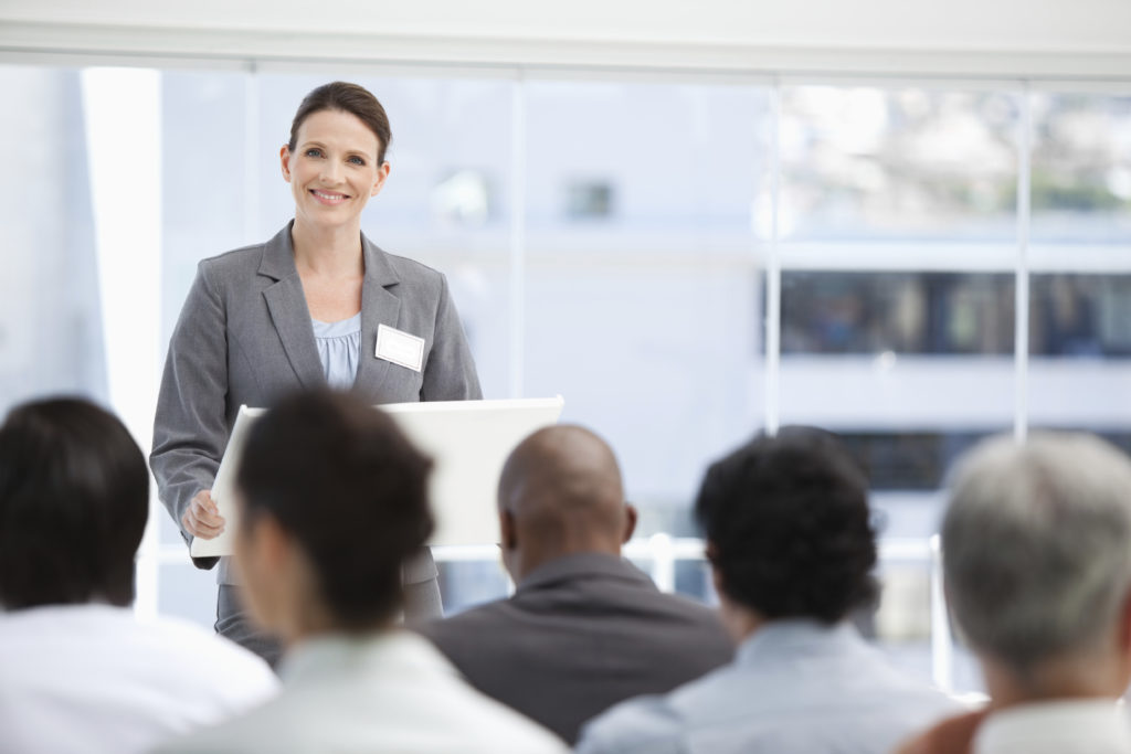 Businesswoman giving a presentation as she looks towards her colleagues with focus on the businesswoman